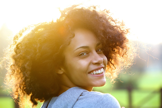 Close up portrait of a cheerful young african american woman smiling outdoors