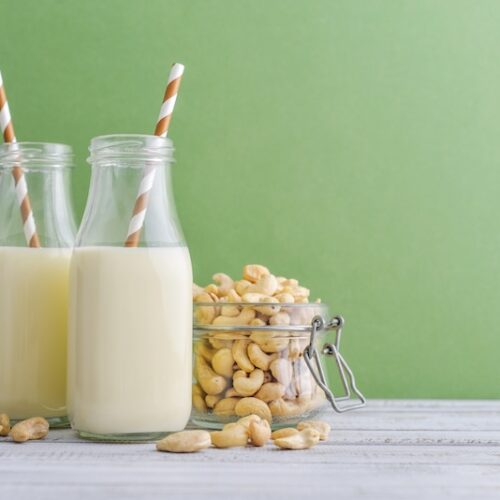 Two bottles of freshly made cashew milk and a jar of raw cashews