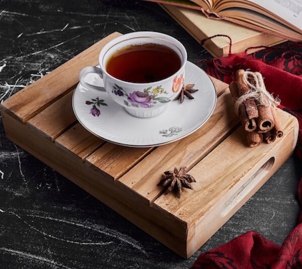 A charming cup of tea with a bundle of cinnamon sticks on a wooden serving board