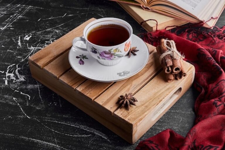 A charming cup of tea with a bundle of cinnamon sticks on a wooden serving board