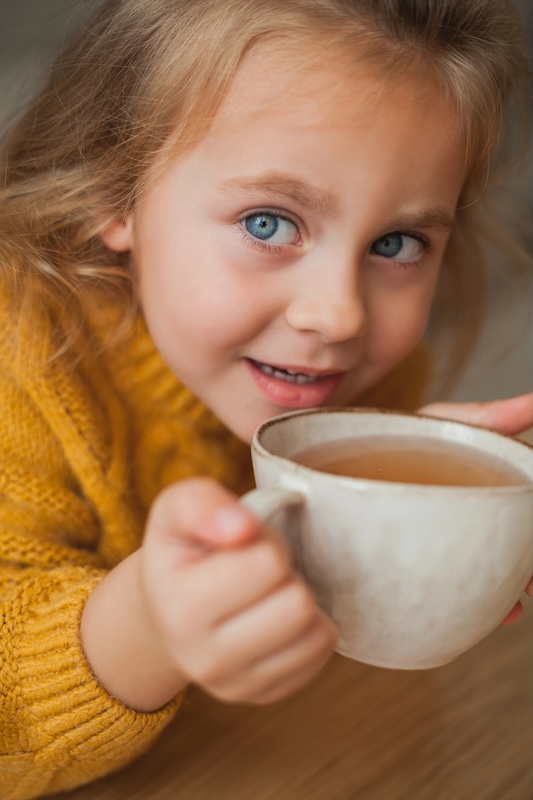 Young girl sipping bone broth from a ceramic mug